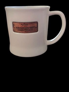 Starbucks 2010 ceramic mug featuring a copper-colored metal badge label